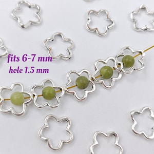 May include: Silver flower-shaped jump rings with a 1.5 mm hole, suitable for 6-7 mm beads. The rings are shown strung on a wire with green beads.