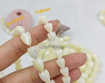 May include: Two strands of off-white, iridescent, tulip-shaped beads. The beads are carved with vertical lines. Text on the image indicates sizes of 8x10mm and 7x8mm. The word craftsextra is printed in the center of the image.