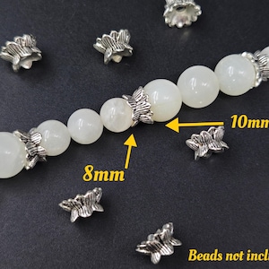 May include: Silver tone metal flower bead caps in two sizes, 8mm and 10mm. The caps are shown on a strand of white beads. "Beads not included" is written at the bottom of the image.