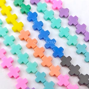 May include: Multiple strands of cross-shaped beads in various colors including yellow, green, blue, purple, pink, orange, and grey. The beads are arranged in parallel lines, and the text CRAFTSEXTRA is visible in the center of the image.