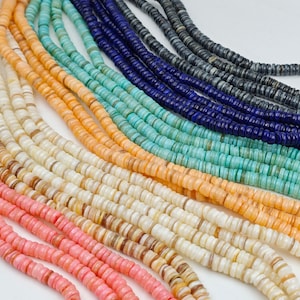 May include: Assortment of colourful shell beads in various shades of pink, orange, white, blue, and green. The beads are arranged in rows, showcasing their unique textures and patterns.