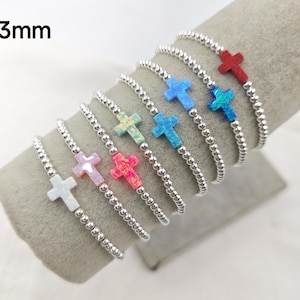 Peut inclure: Un ensemble de huit bracelets en perles argentées avec un charme en forme de croix de 3 mm dans différentes couleurs, notamment rouge, bleu, rose et blanc.