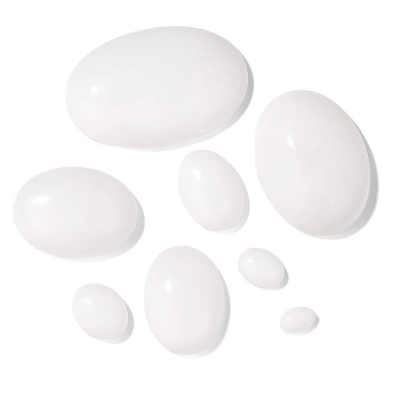 K&ouml;nnte beinhalten: Eine Anordnung wei&szlig;er, oval geformter Tropfen unterschiedlicher Gr&ouml;&szlig;e auf wei&szlig;em Hintergrund. Die Tropfen haben eine gl&auml;nzende Oberfl&auml;che, und ihre Anordnung deutet auf ein Kosmetik- oder Hautpflegeprodukt hin.