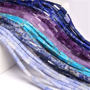 Puede incluir: Surtido de cuentas de piedras preciosas en varios tonos de azul, morado y turquesa. Las cuentas son de forma rectangular y tienen un acabado pulido.