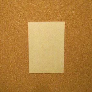 May include: A rectangular, light beige card with a smooth, matte surface. The card is oriented vertically and features a clean, solid-colored front side with no visible patterns, text, or markings, presenting a simple and uniform appearance.
