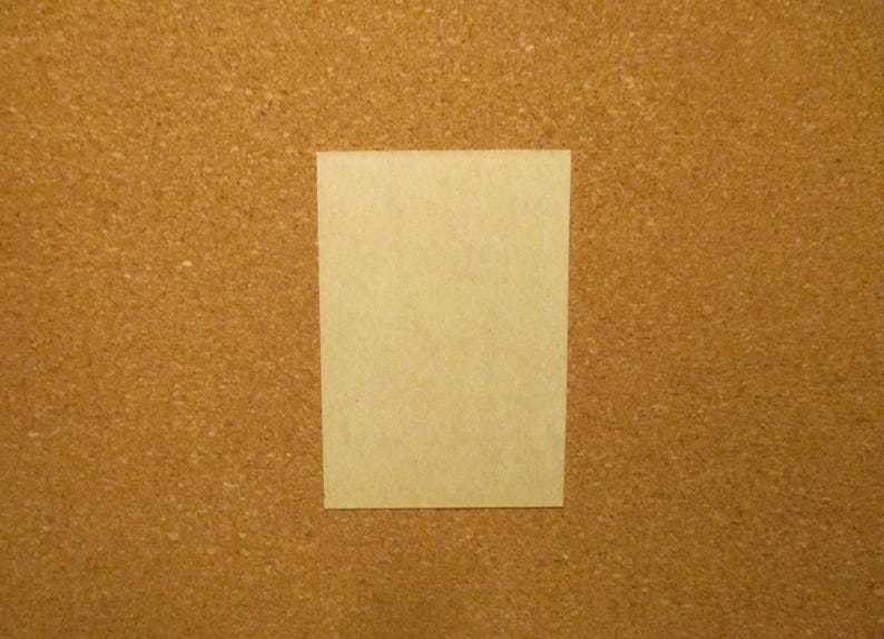 May include: A rectangular, light beige card with a smooth, matte surface. The card is oriented vertically and features a clean, solid-colored front side with no visible patterns, text, or markings, presenting a simple and uniform appearance.
