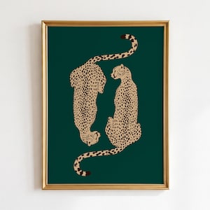 May include: Framed art print with a dark green background, featuring two cheetahs in a stylized illustration. The cheetahs are light brown with dark brown spots. The frame is gold-coloured.