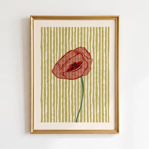 Puede incluir: Impresión artística enmarcada con una flor de amapola roja con un centro oscuro y un tallo verde. El fondo tiene rayas verticales en tonos verde oliva y crema. La obra de arte está encerrada en un marco dorado.