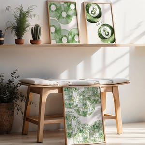 May include: Three framed art prints with watercolor designs. One features green vinyl records, another shows a green eight ball, and the third displays green disco balls. The prints are displayed on a wooden shelf and bench, with potted plants.
