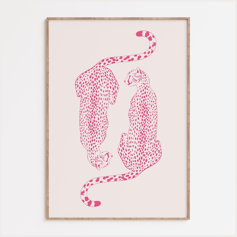 May include: A framed wall art print featuring two cheetahs illustrated in a vibrant hot pink color against a pale blush pink background. The cheetahs are positioned vertically, one facing downward and one facing upward, with detailed spots.