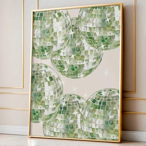 May include: A framed art print featuring several green disco balls with a mosaic tile design. The disco balls are set against a neutral background with scattered white star shapes. The frame is gold.