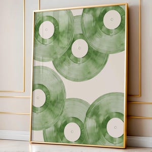 May include: A framed art print featuring a collection of green vinyl records. The records are arranged in a layered pattern against a cream-colored background. The frame is gold.