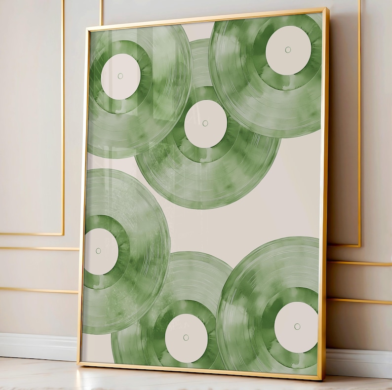 May include: A framed art print featuring a collection of green vinyl records. The records are arranged in a layered pattern against a cream-colored background. The frame is gold.
