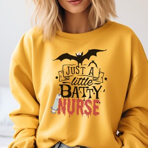 Felpa di Halloween Just A Little Batty Nurse, Felpa girocollo unisex Heavy Blend™, Infermieristica, Halloween in ospedale, camicia da infermiera spettrale
