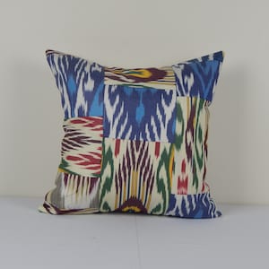 May include: A colorful patchwork pillow cover with a geometric pattern in shades of blue, red, green, yellow, and white.