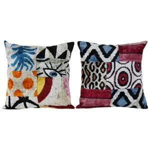May include: Two square decorative pillows with patchwork designs. One pillow features blue, orange, and black patterns. The other pillow has red, white, and blue geometric and animal print patterns. Both pillows are on a white background.
