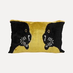 May include: A rectangular velvet throw pillow featuring a vibrant mustard yellow background and two symmetrical black panther heads facing each other. The panther designs include white stitched details for the eyes, whiskers, and teeth.