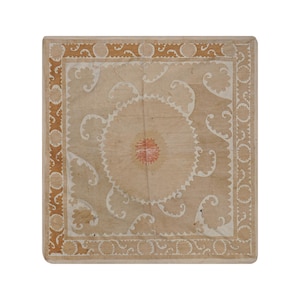 May include: A square, beige textile with a central circular design and ornate white and brown border. The center features a red and white floral pattern, surrounded by white, curved embellishments.