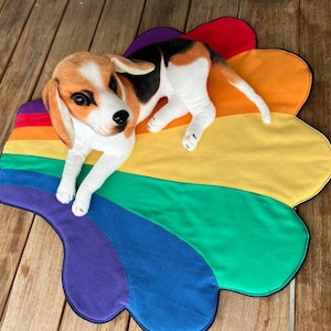May include: A rainbow-colored dog bed in the shape of a cloud with a brown and white dog laying on it.