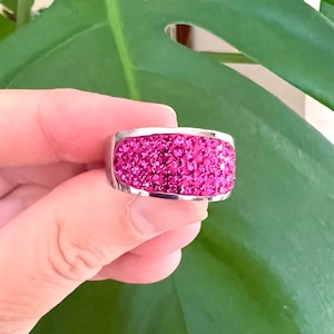 Peut inclure: Une bague en argent avec une bande de strass roses.
