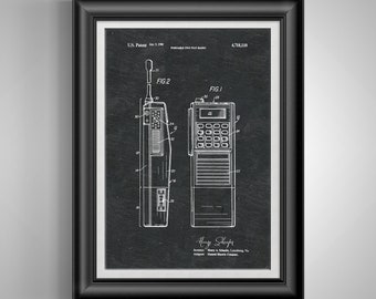 May include: Framed patent print of a portable two-way radio, dated Jan. 5, 1988. The black and white illustration shows two detailed views of the radio's design, including a keypad, antenna, and speaker. The print is set against a dark background.