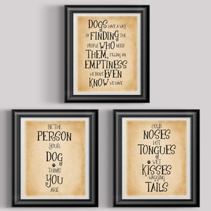 May include: Three framed prints with black frames and tan backgrounds. The prints feature black text with dog-themed quotes. One print reads "Dogs have a way of finding the people who need them." Another says "Be the person your dog thinks you are."