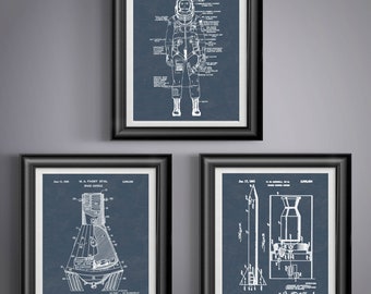 May include: Three framed prints with white diagrams on a dark blue background. The top print shows a spacesuit diagram. The bottom left print shows a space capsule diagram. The bottom right print shows a rocket diagram.