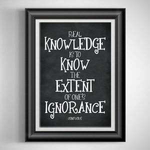 May include: A framed print with a black frame and a white border. The print features white text on a black background, with the quote "REAL KNOWLEDGE IS TO KNOW THE EXTENT OF ONE'S IGNORANCE" attributed to Confucius.