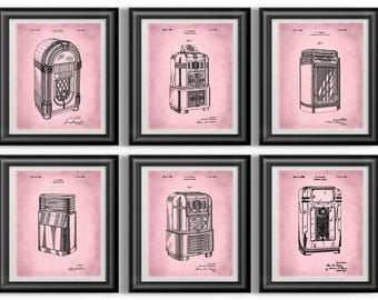 May include: Six framed prints featuring vintage jukebox designs in black ink on a pink background. Each print is in a black frame. The jukeboxes are depicted in a technical drawing style, showcasing their various components and designs.