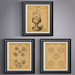 May include: Three vintage patent drawings for dice, framed in black. The first drawing shows a dice tower with a glass dome. The second drawing shows a dice with different numbers on each side. The third drawing shows a dice with different letters on each side.