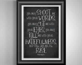May include: Framed print with a black frame and white matting. The print features a quote by Maya Angelou in white script on a dark gray background. The quote reads, "You may shoot me with your words...but still, like air, I'll rise."
