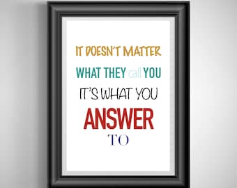 May include: A framed print with the quote "IT DOESN'T MATTER WHAT THEY call YOU IT'S WHAT YOU ANSWER TO." The text is in various colors: gold, teal, black, red, and blue. The frame is black and the background is white.