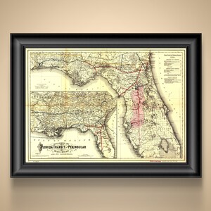 May include: Framed vintage map of Florida, featuring the Florida Transit & Peninsular Railroad. The map is in sepia tones with red lines indicating railroad routes. The map is framed in a black wooden frame.