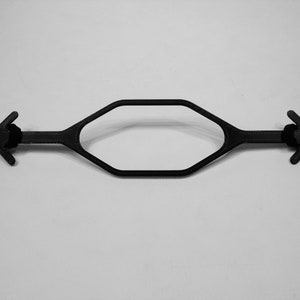 May include: A black plastic hexagonal shaped object with two black arrow-shaped handles on either end.
