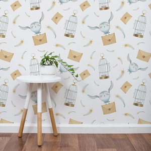 May include: White table with a white top and brown wooden legs. The table is in front of a white wall with a repeating pattern of owls, cages, and envelopes. The pattern is in shades of blue, brown, and yellow.