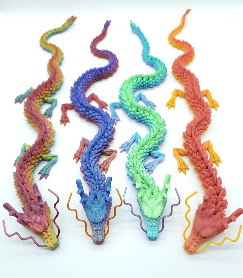 May include: Four articulated dragon figurines in rainbow hues. Each dragon features a distinct colour gradient, with shades of red, orange, yellow, green, blue, and purple. The dragons are displayed on a white surface, highlighting their intricate design.