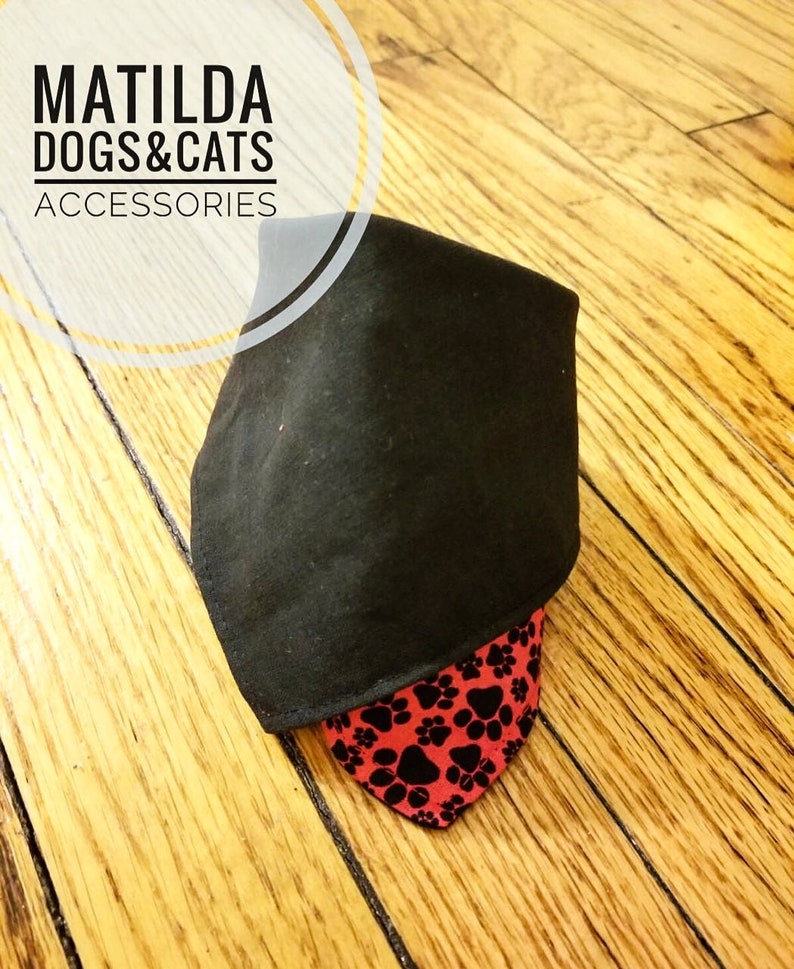 May include: Black bandana with red paw print fabric underneath. The bandana is folded in half and the text "MATILDA DOGS & CATS ACCESSORIES" is visible in the top left corner.