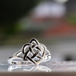 May include: A silver ring with a Celtic knot design in the shape of a heart.