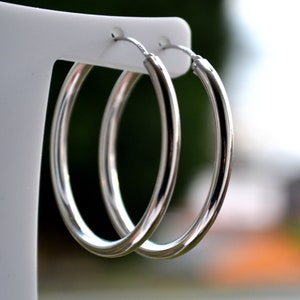 May include: A pair of silver hoop earrings. The earrings are simple and elegant, and they would be a great addition to any jewellery collection.