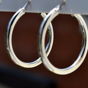 May include: A pair of silver hoop earrings hanging on a display stand.