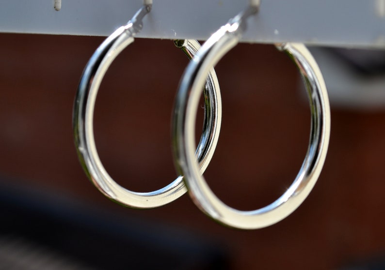 May include: A pair of silver hoop earrings hanging on a display stand.
