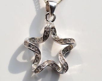 May include: A silver necklace with a star-shaped pendant. The star is made of twisted silver wire and is set with small clear stones.