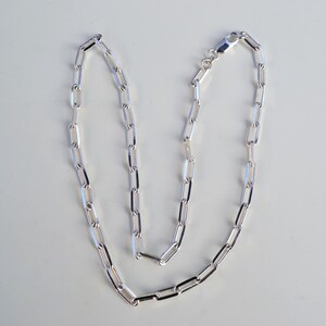 May include: A silver chain necklace with a simple, linked design. The chain is made of small, rectangular links.
