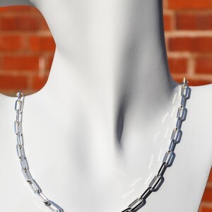 May include: A silver chain necklace with a simple, linked design. The chain is made of small, rectangular links.