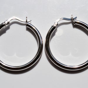May include: A pair of silver hoop earrings. The earrings are round and have a smooth finish.