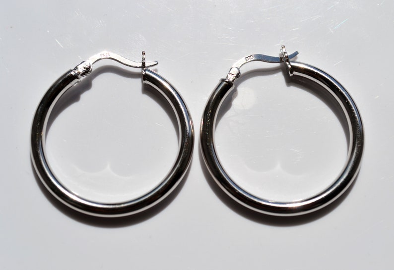 May include: A pair of silver hoop earrings. The earrings are round and have a smooth finish.
