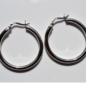 May include: A pair of silver hoop earrings. The earrings are round and have a smooth finish.
