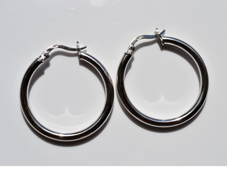 May include: A pair of silver hoop earrings. The earrings are round and have a smooth finish.
