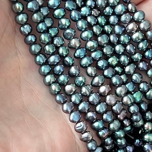 May include: A strand of dark grey freshwater pearls with a slight iridescent sheen. The pearls are round and smooth, and they are strung on a clear thread.