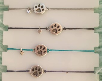 May include: Six colorful bracelets with silver paw print charms. The bracelets are displayed on a white background.